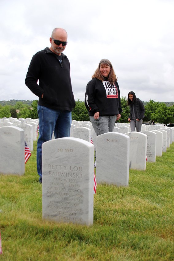 Tom Barwinski, left, his wife Lorie and their daughter Emma view Tom's parents' headstone at Fort Logan. "There are so many hidden life stories here," Emma said. "Behind each name is a life, compressed into just a few lines."